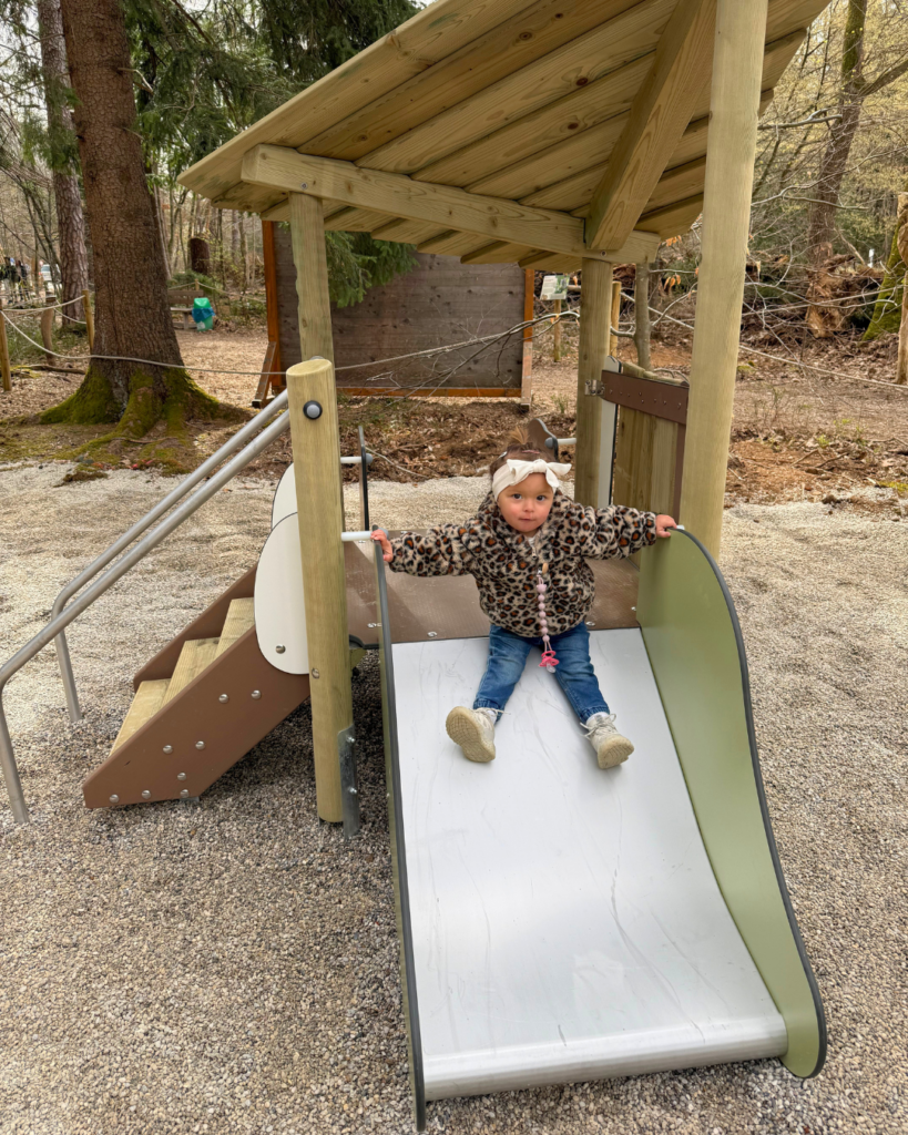 Ein Kleinkind welches auf einem Spielplatz von einer Rutsche runter rutscht.